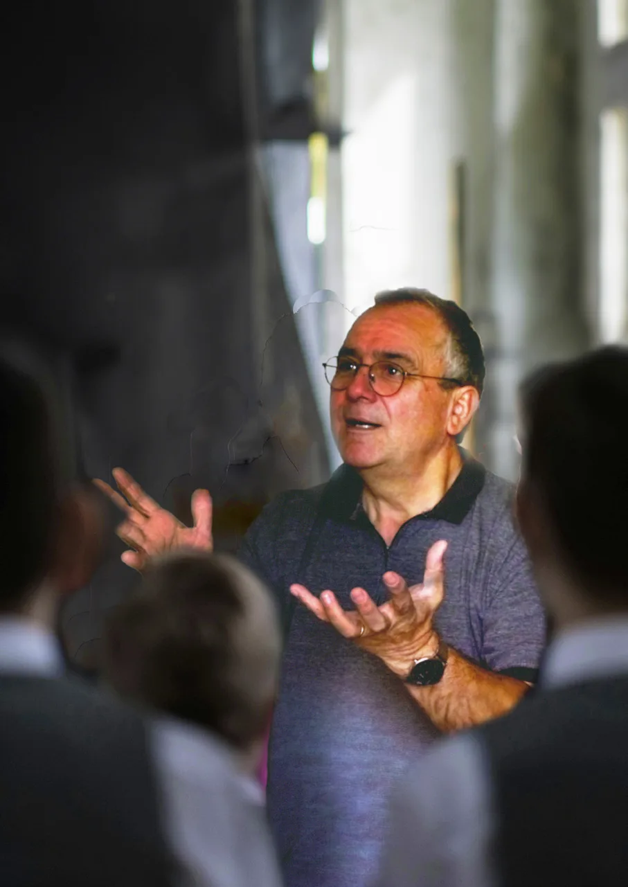 Un chef d’ensemble dirige des choristes vus de dos.